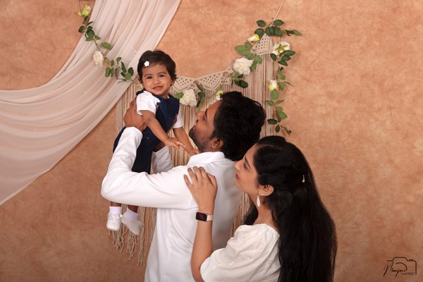 Parents lifting their smiling toddler at a warm studio set