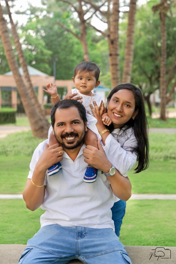 Father carrying a toddler on his shoulders beside the mother