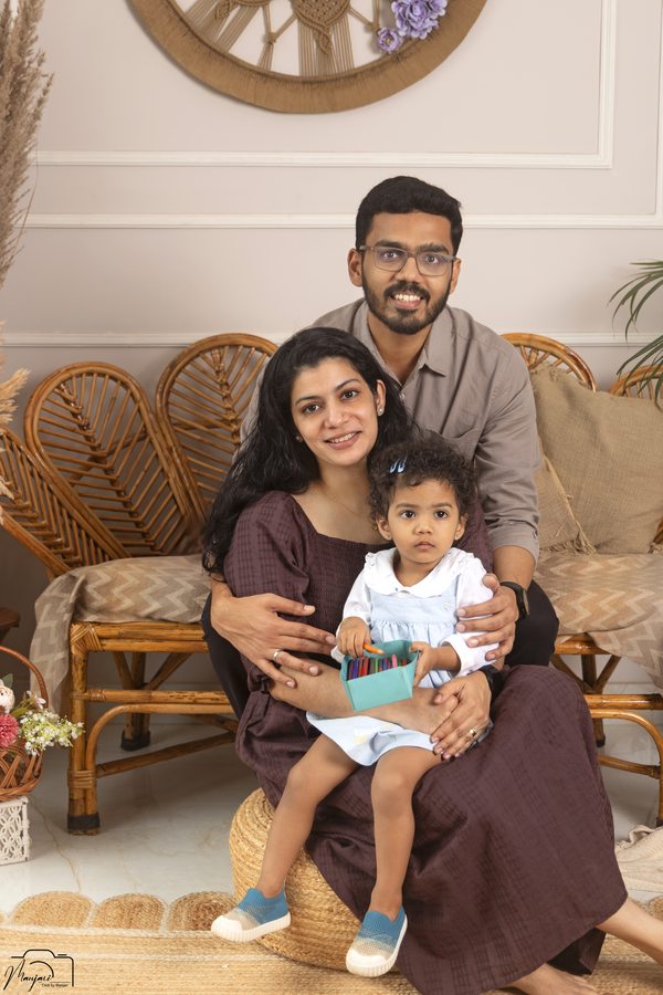 Parents and baby seated together in a warm indoor portrait