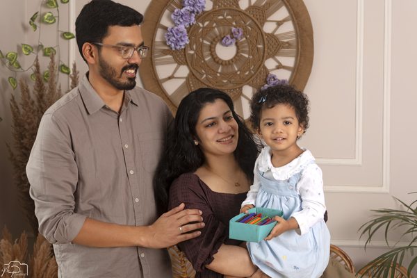 Parents and toddler smiling together in a bright indoor portrait