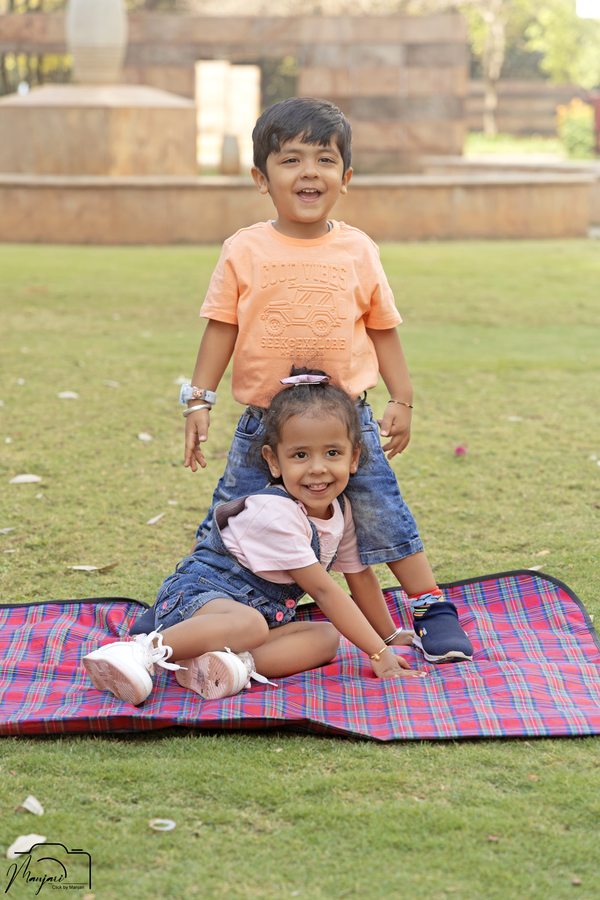 Two children sitting together on a picnic blanket in a garden