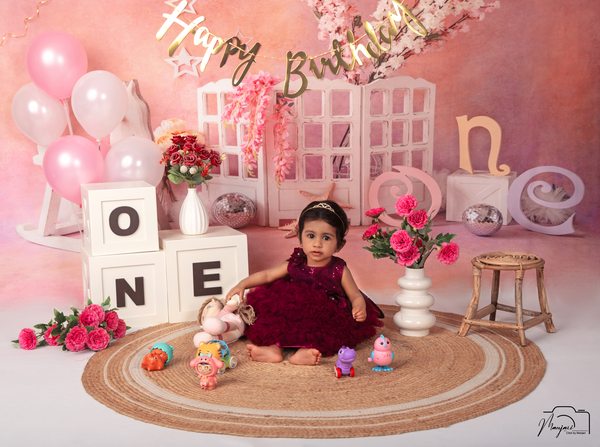 Baby celebrating a first birthday in a burgundy outfit