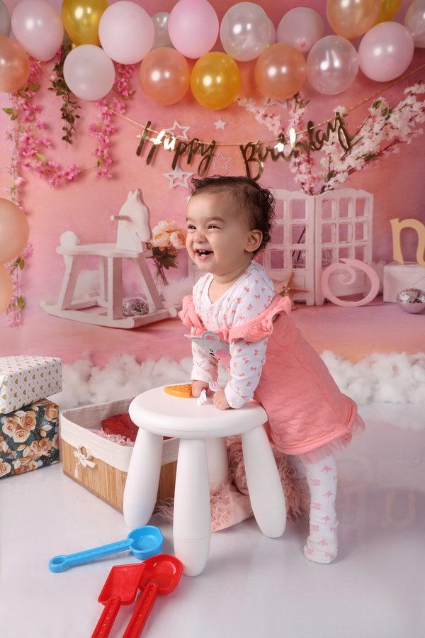 Laughing toddler at a pink birthday cake table