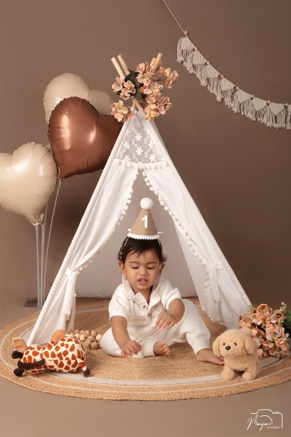Toddler wearing a crown at a neutral birthday set
