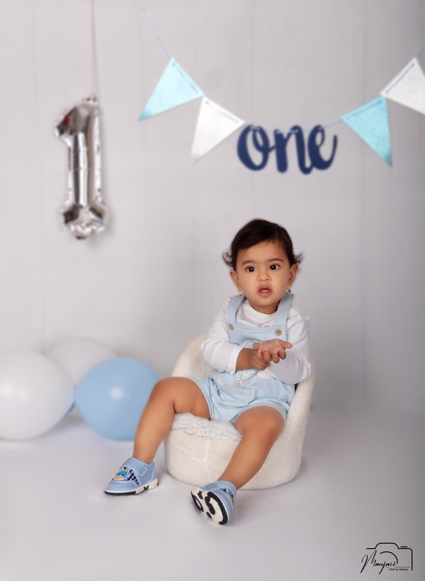 Baby seated with blue balloons at a first-birthday set
