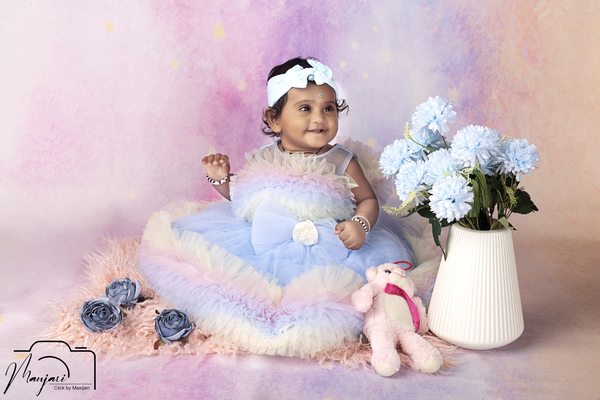 Baby in a pastel dress surrounded by blue flowers