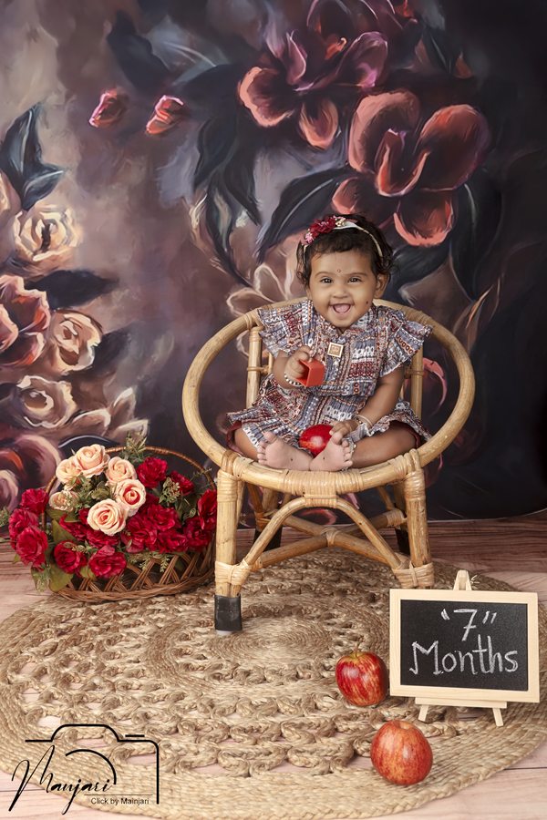 Baby seated in a vintage chair against a floral backdrop