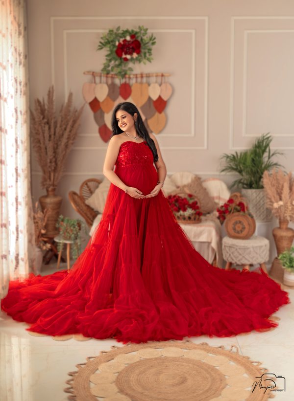 Expectant mother in a flowing red gown in an elegant studio