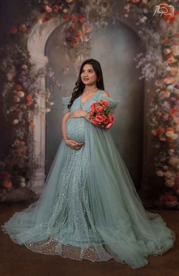 Expectant mother in a mint gown holding a bouquet