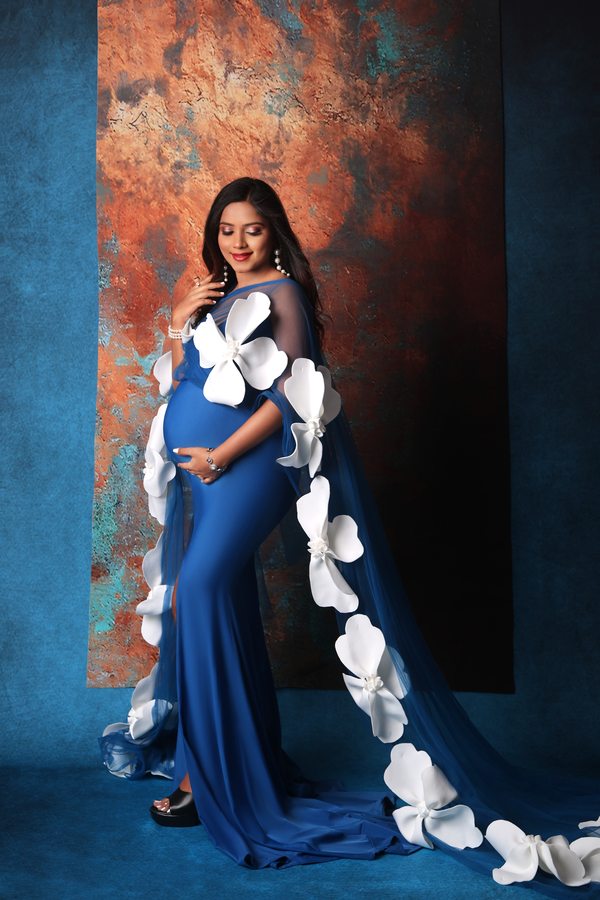 Fine-art maternity portrait in royal blue with white floral accents