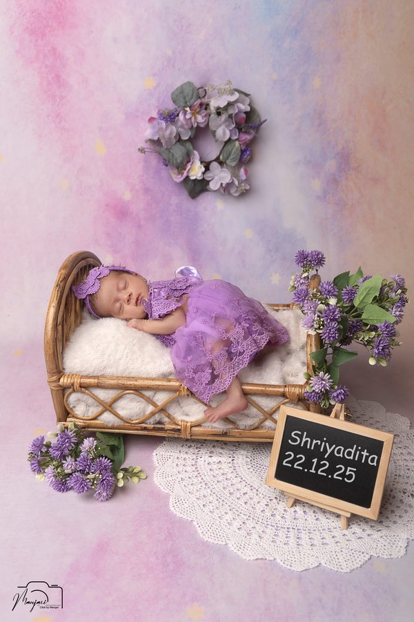 Newborn resting in a lavender miniature bed with flowers