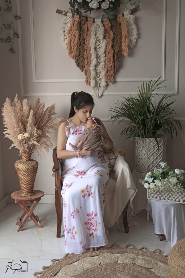 Baby wrapped in floral white fabric in a warm boho studio set