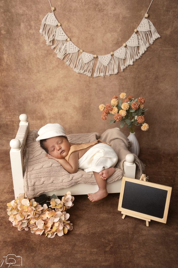Sleeping newborn in white on a miniature wooden bed