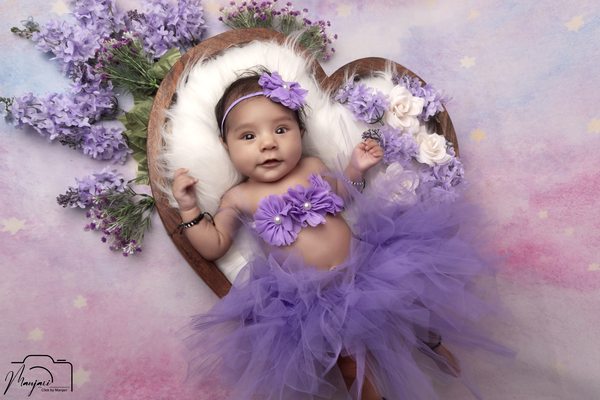 Newborn resting in a purple floral nest