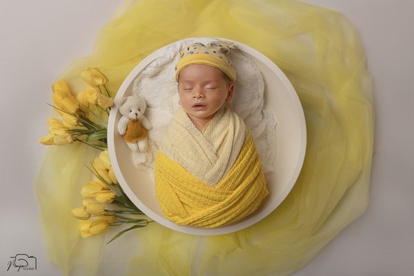 Sleeping newborn in yellow with flowing fabric