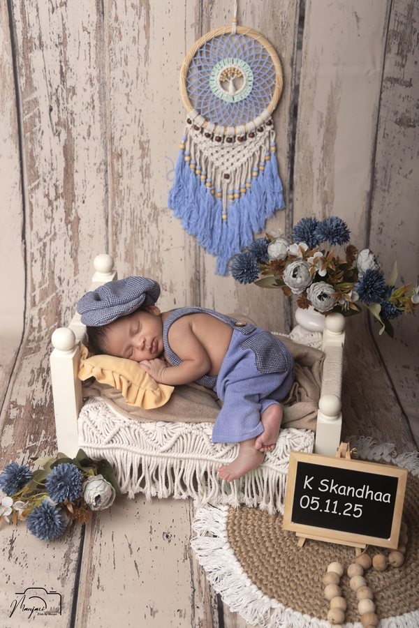 Newborn sleeping in blue on a rustic miniature bed