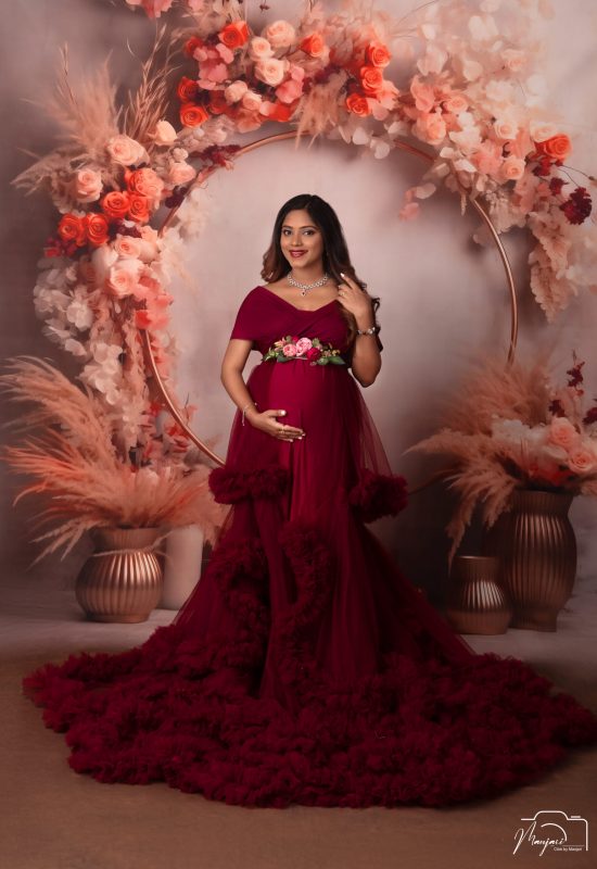Maternity portrait in a burgundy gown surrounded by flowers